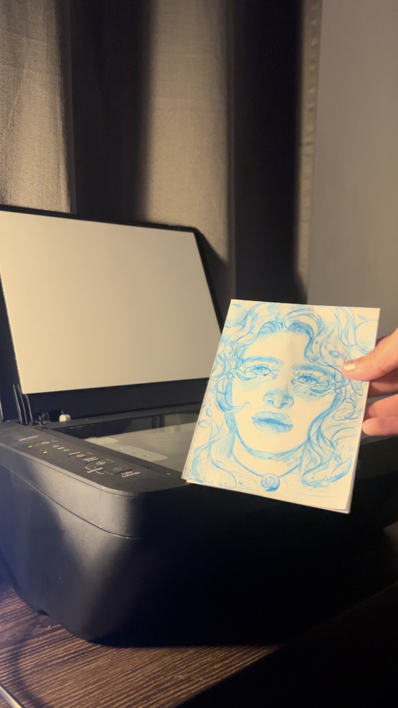 A designer's hand about to scann a ink portrait. Process of mixed media intervention in photoshop.